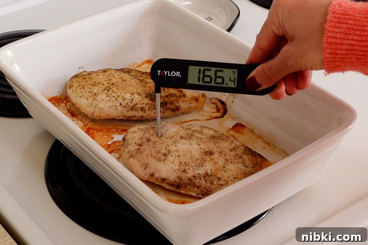 Tender Oven-Baked Chicken Breasts with Garlic and Herbs 6 A woman checking the internal temperature of a chicken breast.