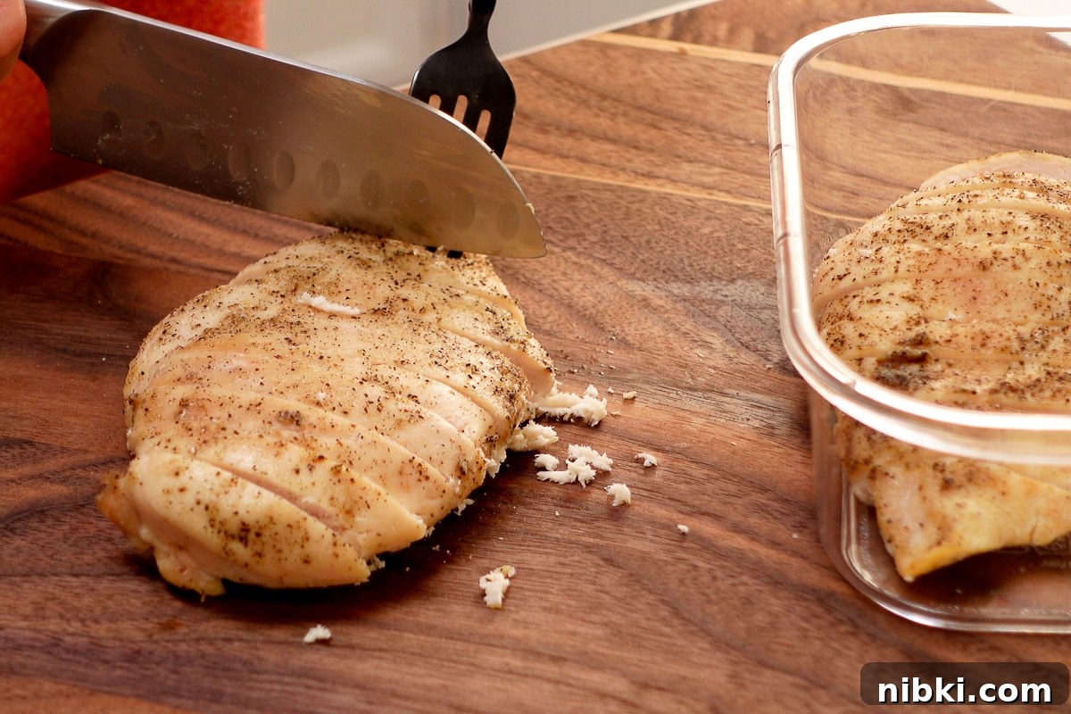 Tender Oven-Baked Chicken Breasts with Garlic and Herbs 7 A woman slicing a chicken breast.