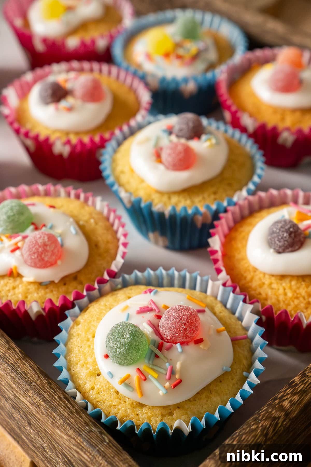 Fairy cakes decorated in icing, colourful sprinkles and sweets