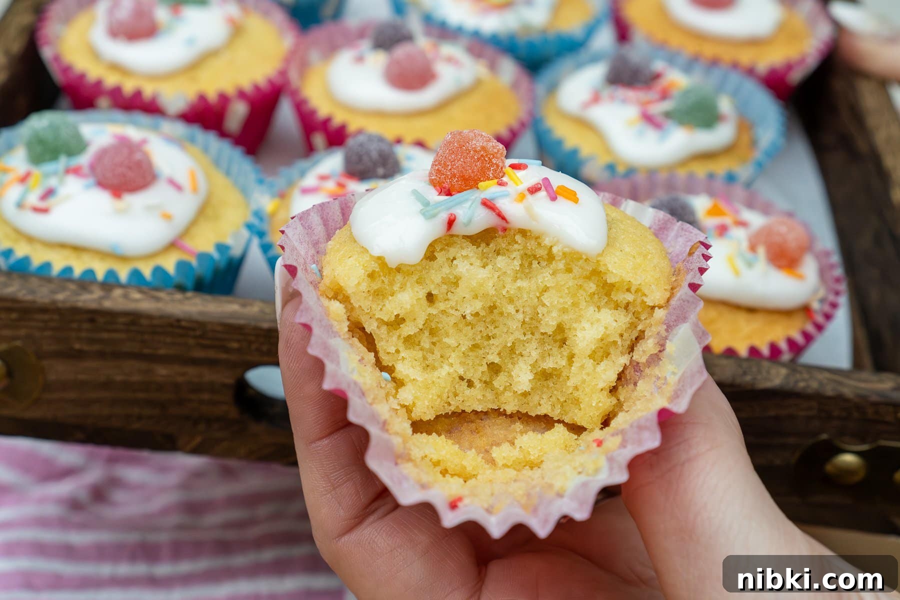 A fairy cake that has had a bite out of it showing the fluffy texture of the cake