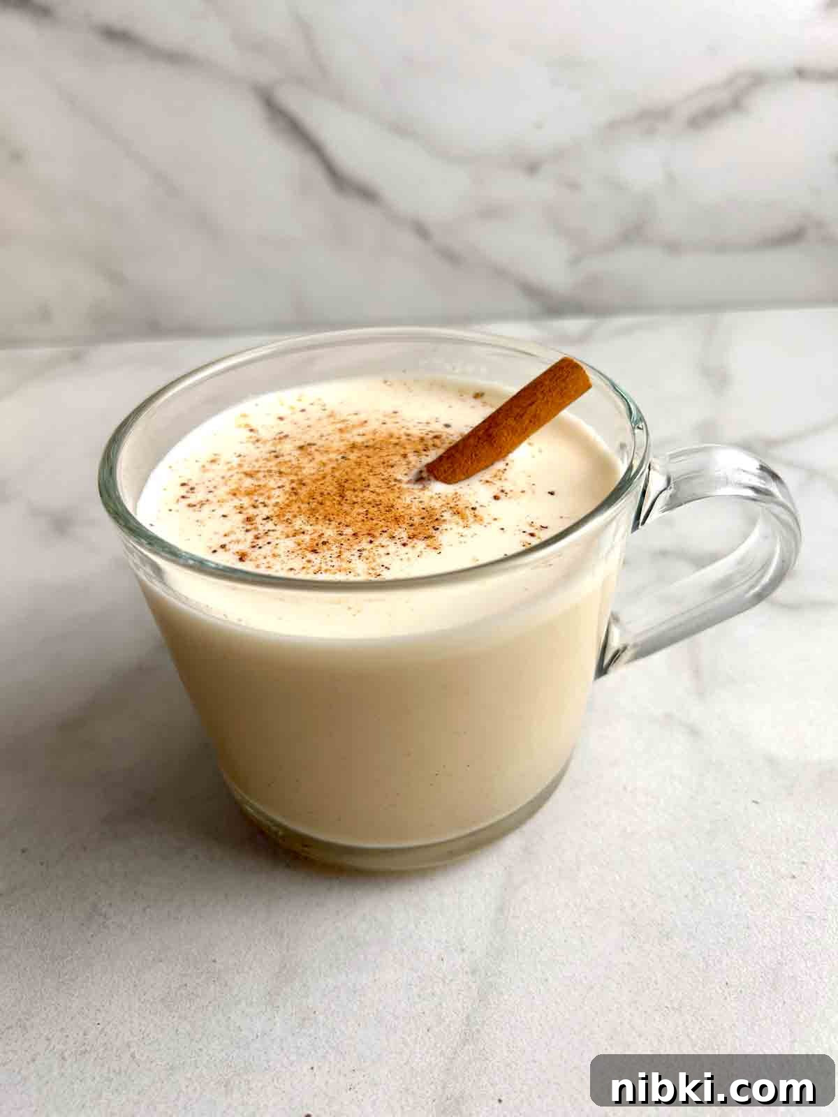 How to Make Classic Homemade Eggnog with Rum 2 cup of eggnog with cinnamon stick and powder on top.