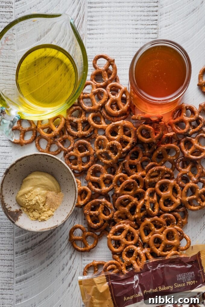 Overhead view of a wooden countertop scattered with a bag of mini pretzels, olive oil, honey, whole grain mustard, dried mustard, and garlic powder, ready to mix into a homemade seasoning blend.