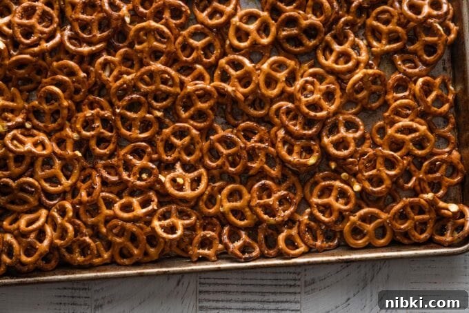 Landscape-oriented image of homemade honey mustard pretzels spread out on a large baking pan and just taken out of the oven.