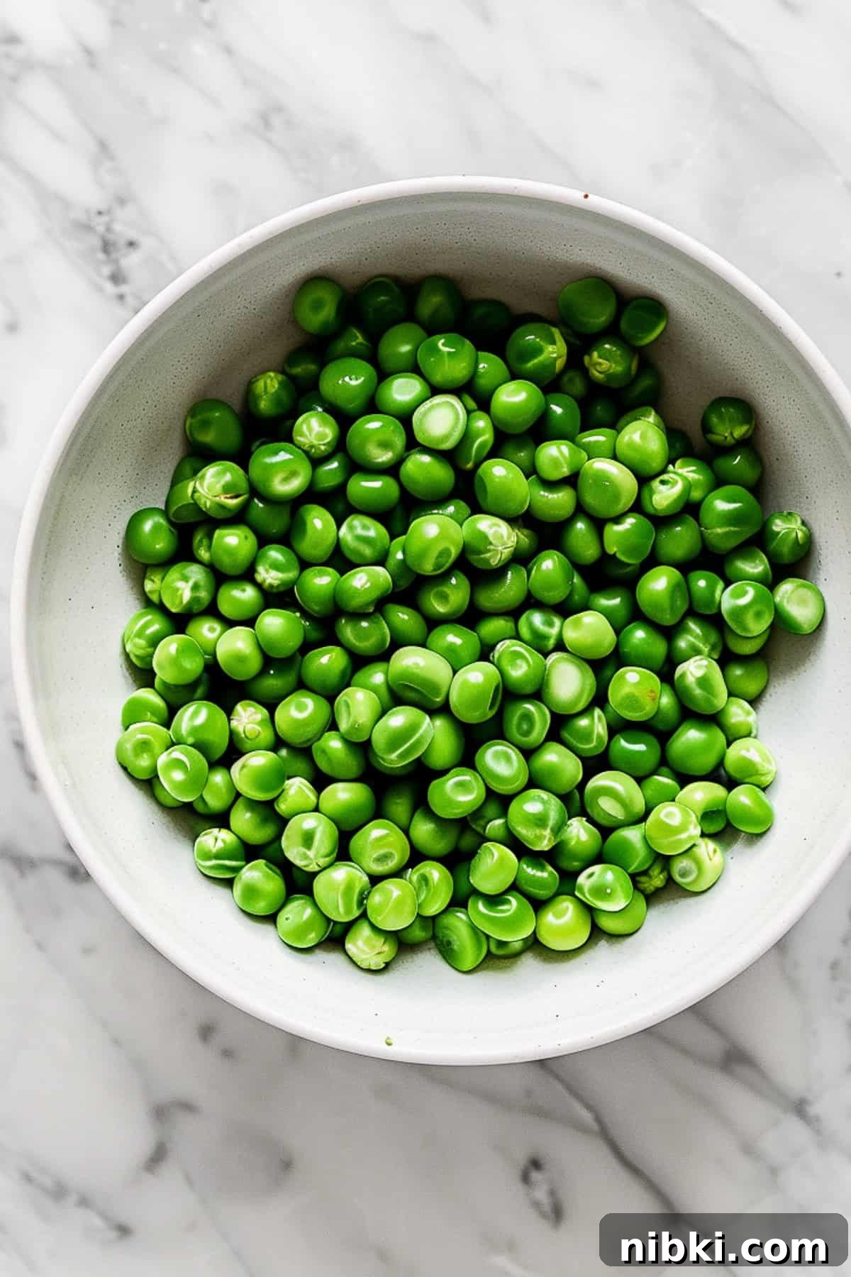 Green peas in a white bowl for making hummus.