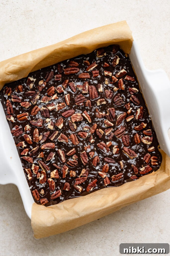 Overhead of a square pan filled with chocolate and pecan topped fudge.