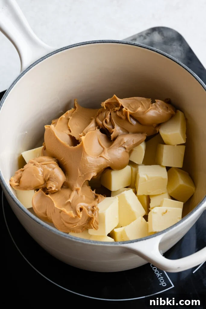 Creamy peanut butter and cubes of butter in saucepan.