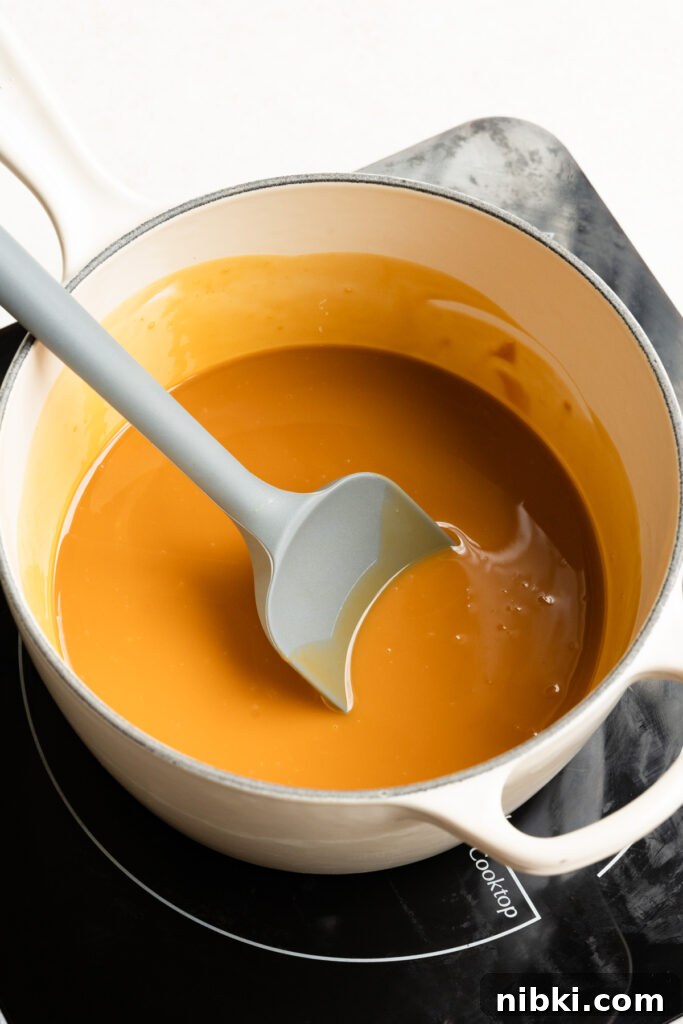 Melted peanut butter mixed with butter in a saucepan with a spatula.