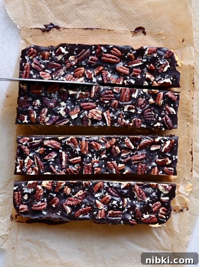 Overhead of chocolate and pecan topped fudge being cut into sections with a knife.