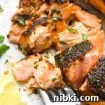 A fork with a bite of flaky blacked salmon resting on a plate.