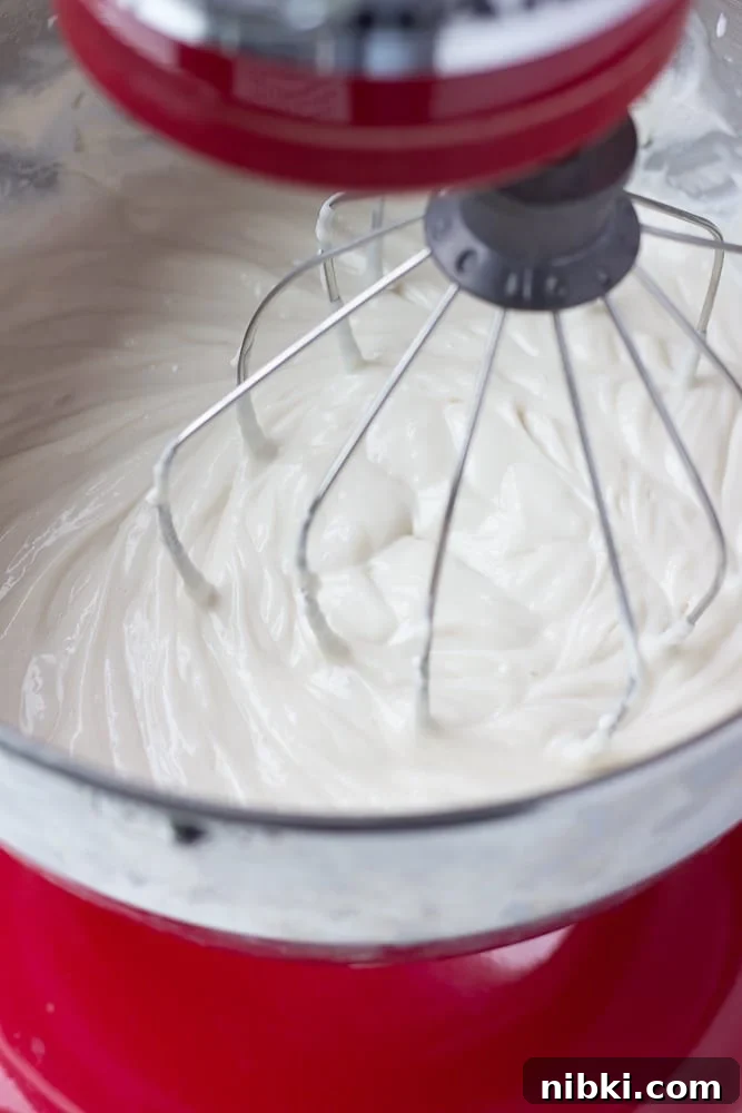 How to Make a Creamy Vegan Cheesecake 6 white cream in a red kitchen aid mixer with a whisk attachment