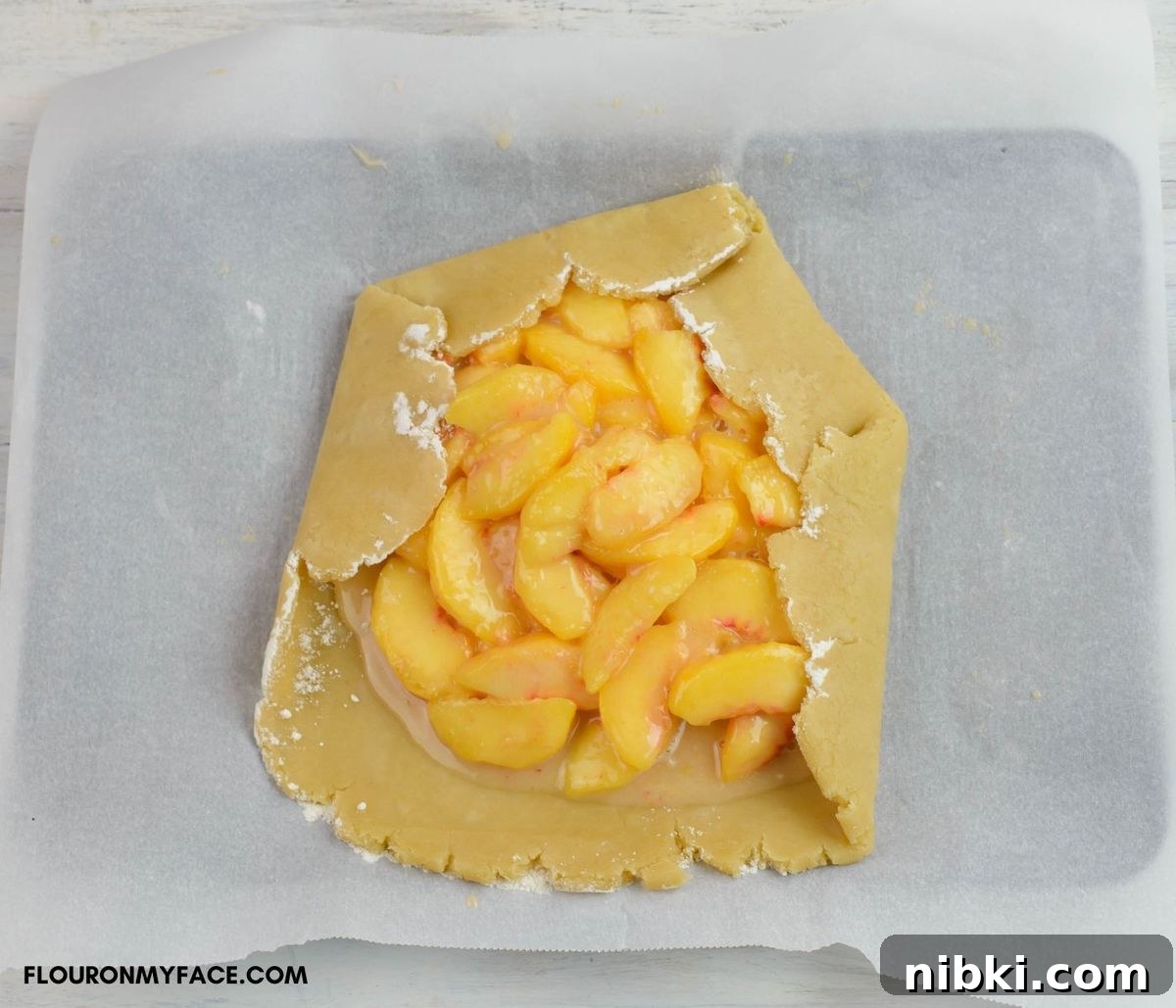 Folding the crust for a peach Galette over the filling.