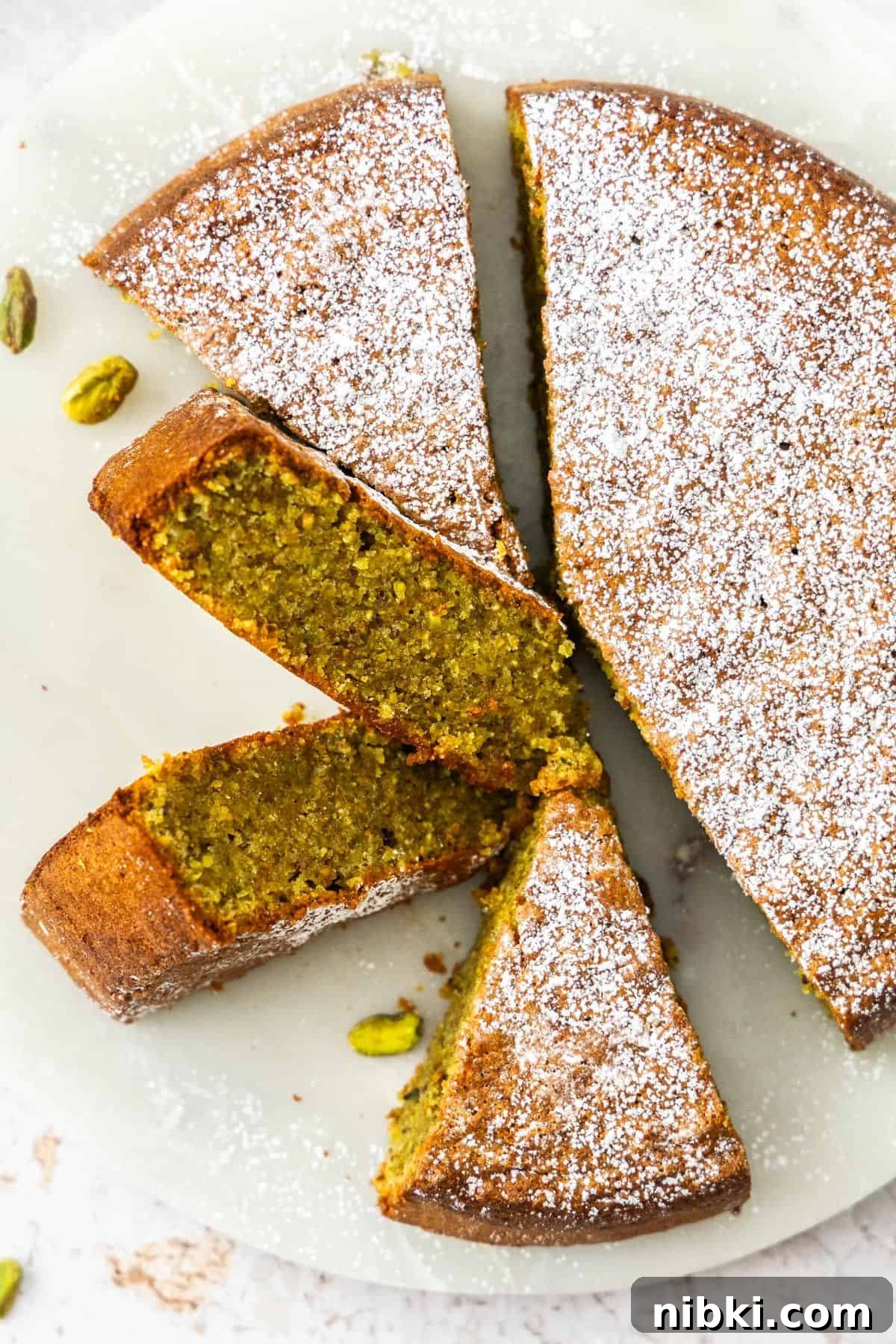 Decadent Flourless Pistachio Cake Recipe: Gluten-Free Dessert 6 Pistachio Cake dusted with powdered sugar and sliced.