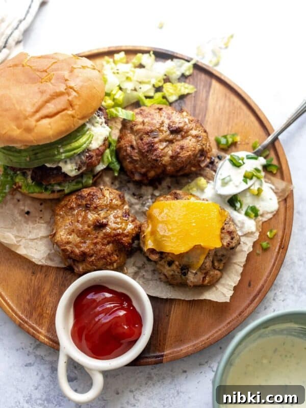 Turkey Burgers on buns on a plate and spoon on the side with jalapeño mayo.