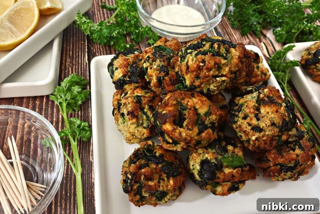 Air Fryer Spinach Balls: Crispy Appetizer Recipe 3 spinach balls on a square plate piled up in a pyramid on the right with lemon wedges and toothpicks on the left