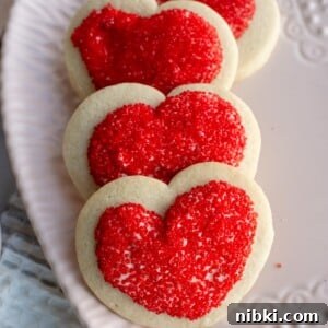 No-Chill Soft Sugar Cookies That Stay Tender and Chewy 16 Valentine heart shaped sugar cookies on a heart plate.