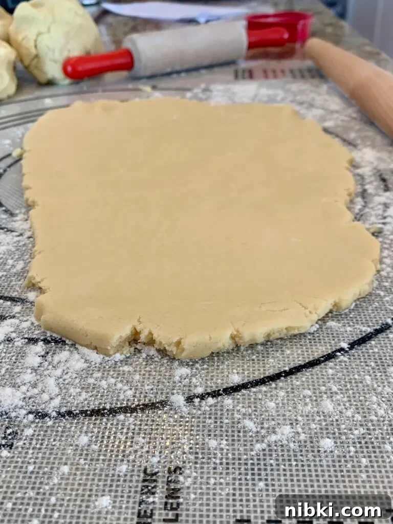 No-Chill Soft Sugar Cookies That Stay Tender and Chewy 7 Dough is rolled out on a dough mat with sprinkled flour around.