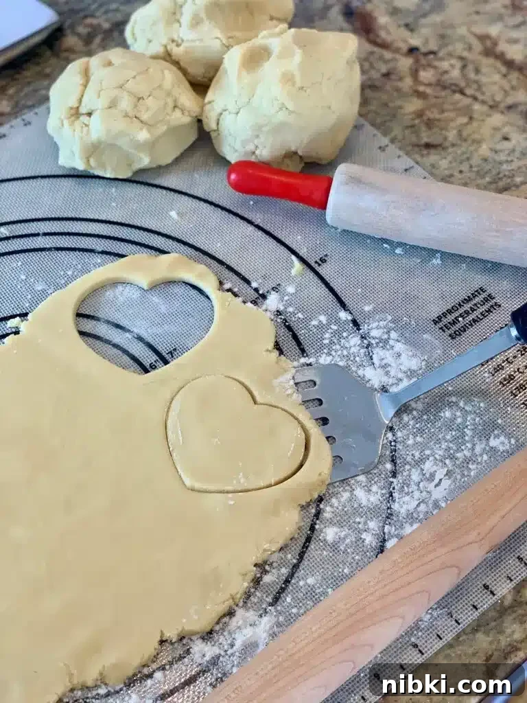 No-Chill Soft Sugar Cookies That Stay Tender and Chewy 9 Two heart shapes are cut out of rolled out dough on a kitchen counter.