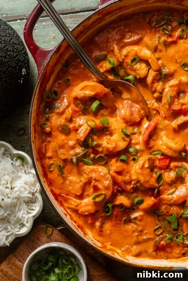 Authentic Louisiana Dirty Rice Recipe 10 shrimp creole in a large pot with a serving spoon next to a bowl of rice.