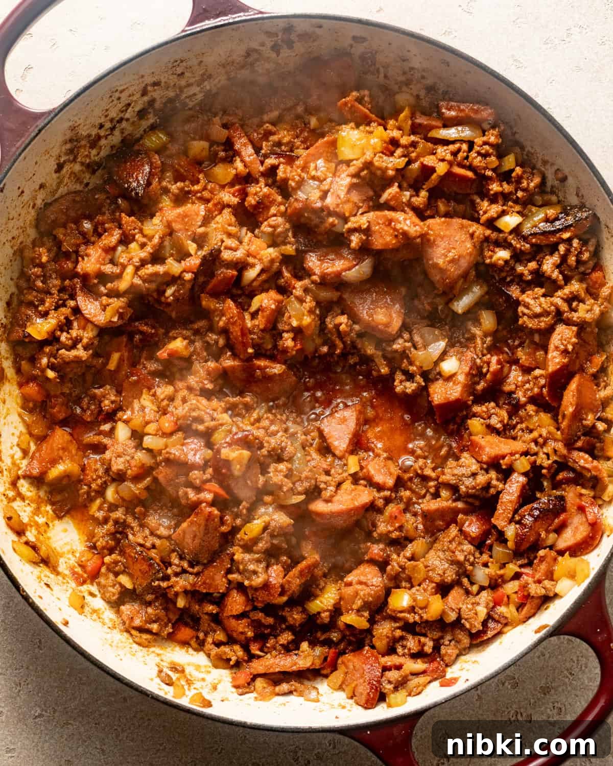 Authentic Louisiana Dirty Rice Recipe 4 sausage and vegetables in a pot with ground beef, seasonings, and tomato paste.