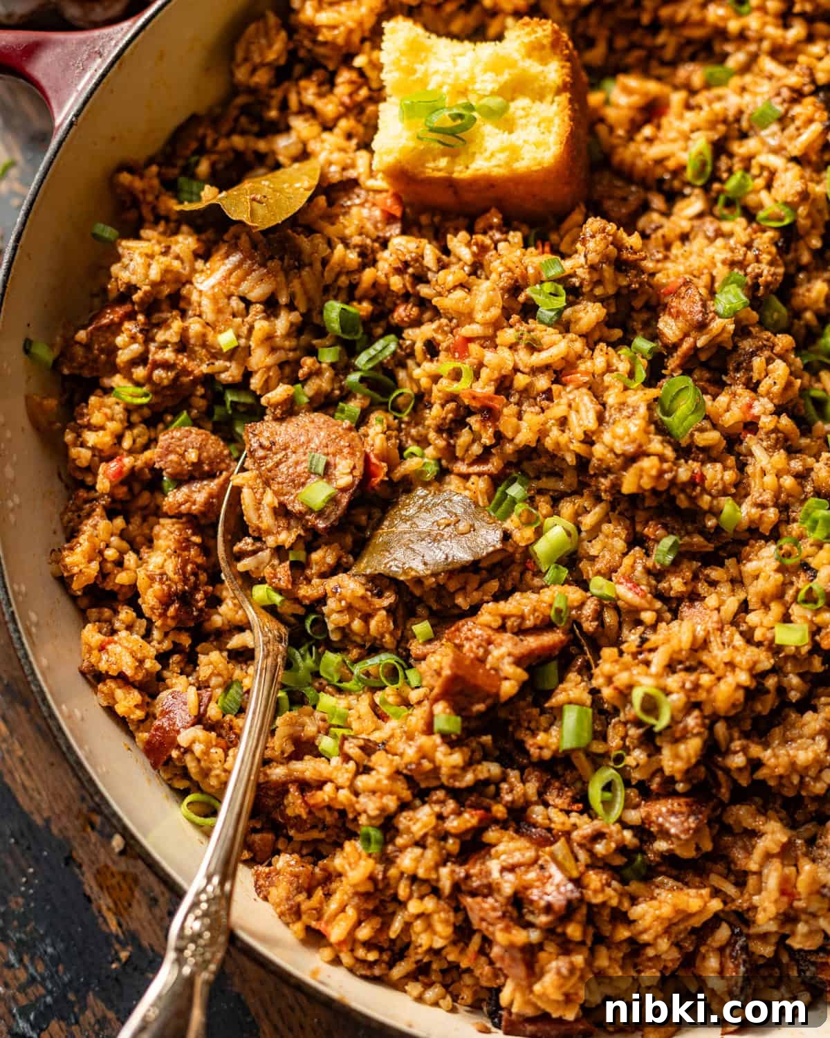 Authentic Louisiana Dirty Rice Recipe 6 up close photo of louisiana dirty rice in a skillet with a serving spoon.