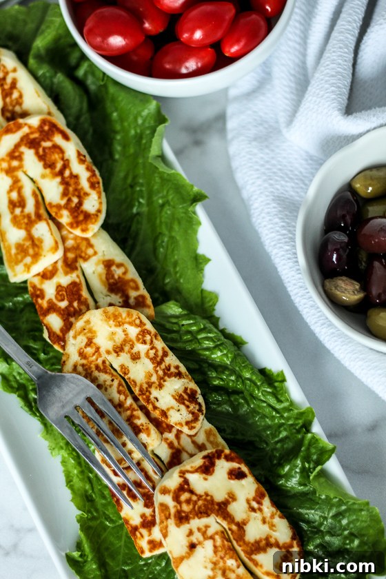 Crispy Grilled or Pan-Fried Halloumi Recipe 2 Freshly fried halloumi slices arranged on a bed of lettuce next to a red cabbage salad.