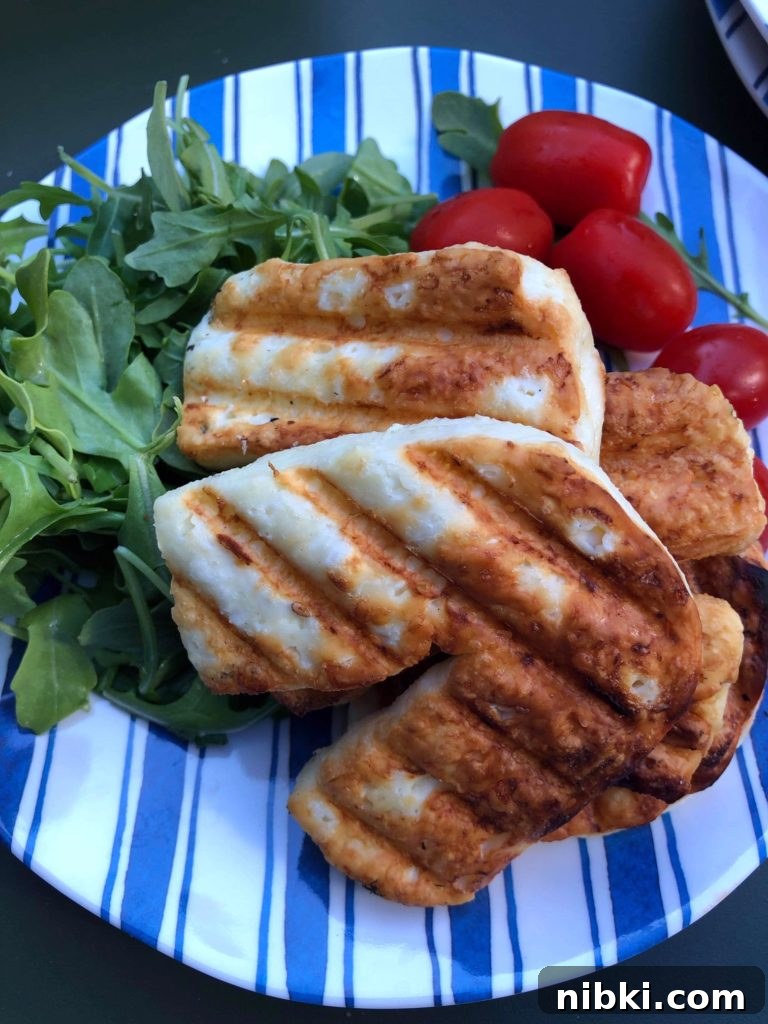 Crispy Grilled or Pan-Fried Halloumi Recipe 5 Freshly grilled slices of halloumi cheese on a bed of arugala and baby tomatoes.