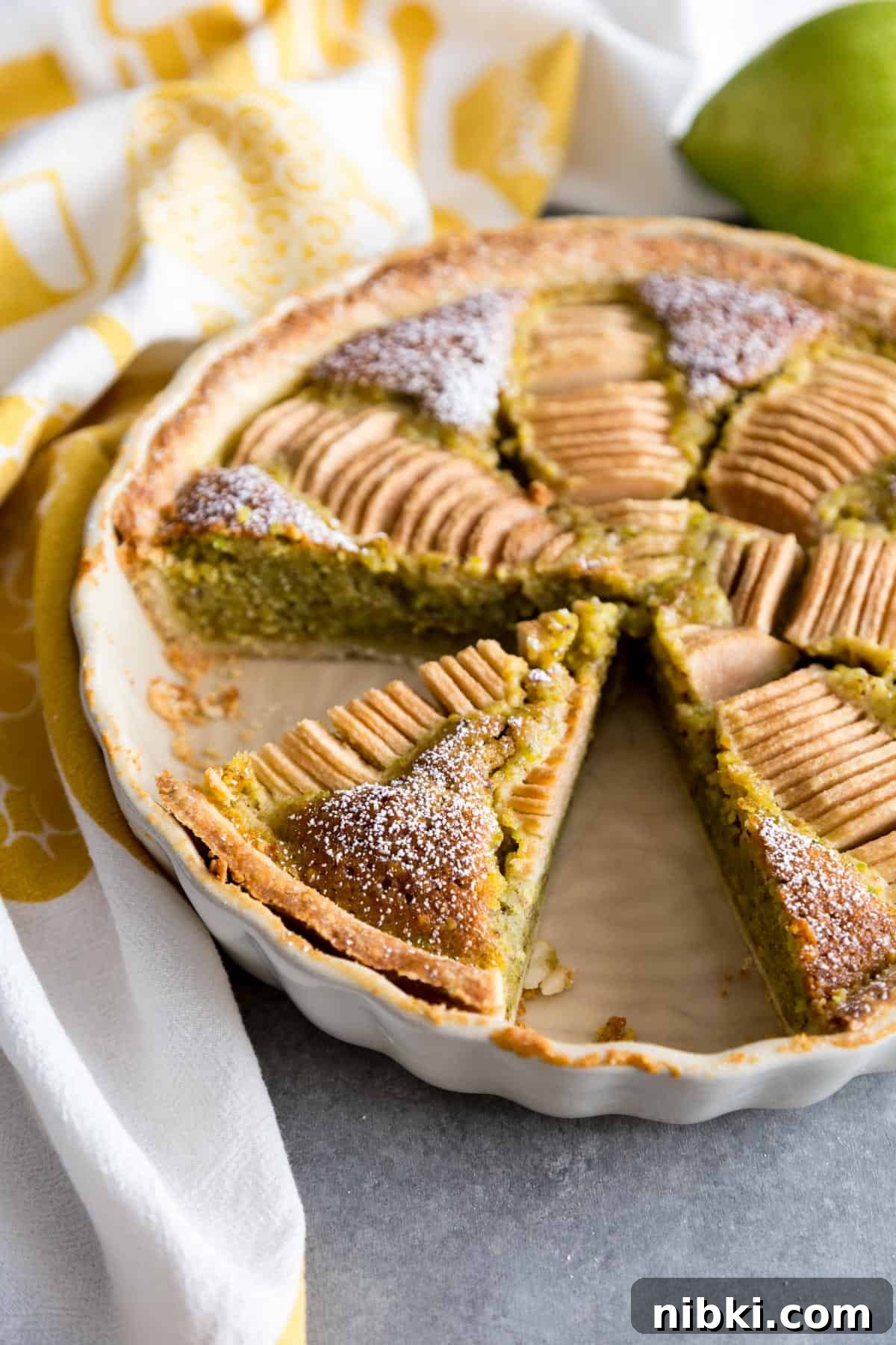 A pear and frangipane tart with two slices removed.