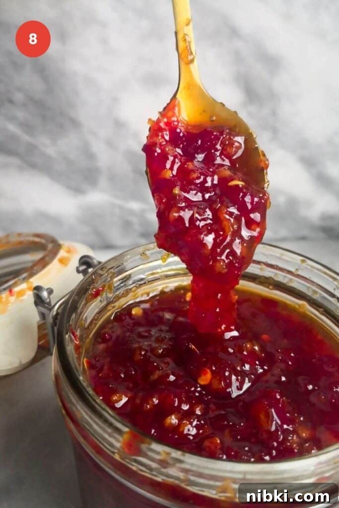 30-Minute Sweet Chili Jam Recipe 10 Spooning thickened chili jam into a jar.