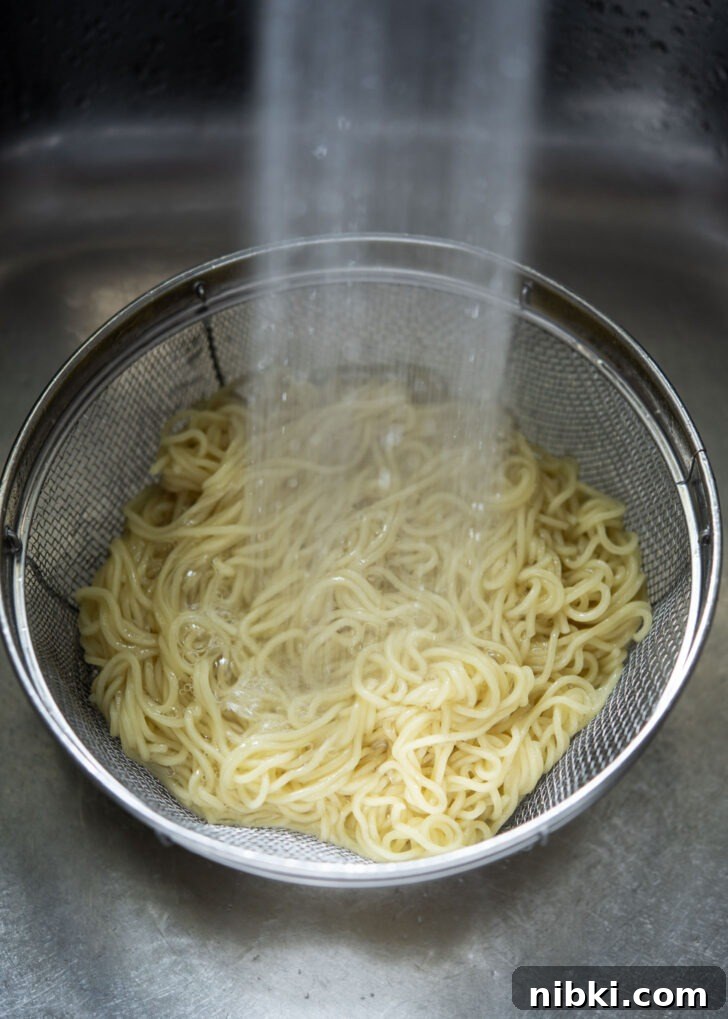 20-Minute Beef Noodles with Gochujang Sauce 4 Cooked wheat noodles being rinsed under the cold water