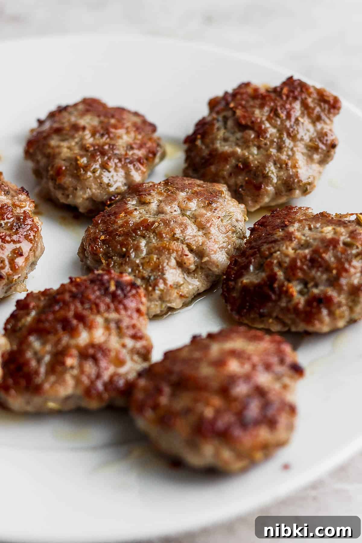 Cooked sausage patties on a white plate.
