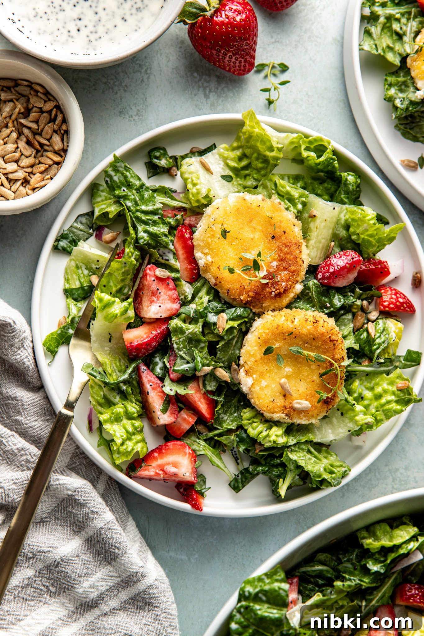 Strawberry Poppyseed Salad with Goat Cheese Croutons 11 Plated servings of strawberry poppyseed salad on small white plates, each topped with crispy goat cheese rounds.