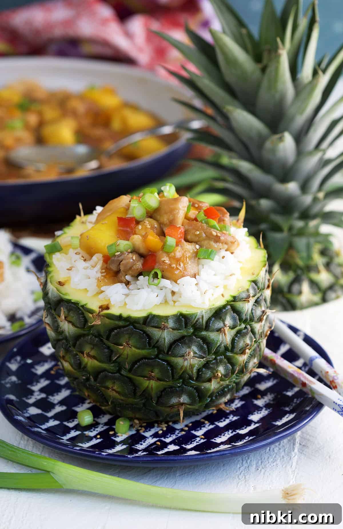 A pineapple is filled with rice and pineapple chicken.