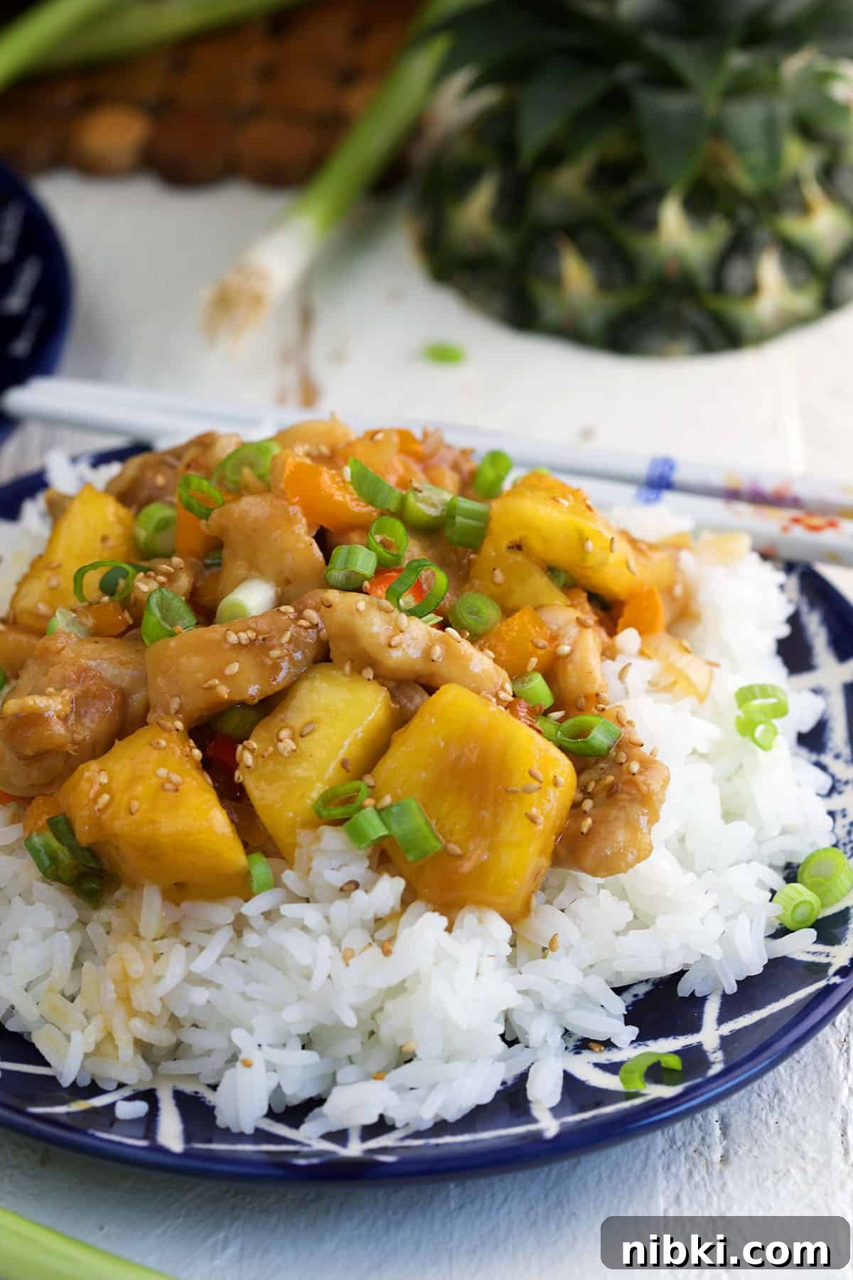 Pineapple chicken is placed on top of a serving of white rice.