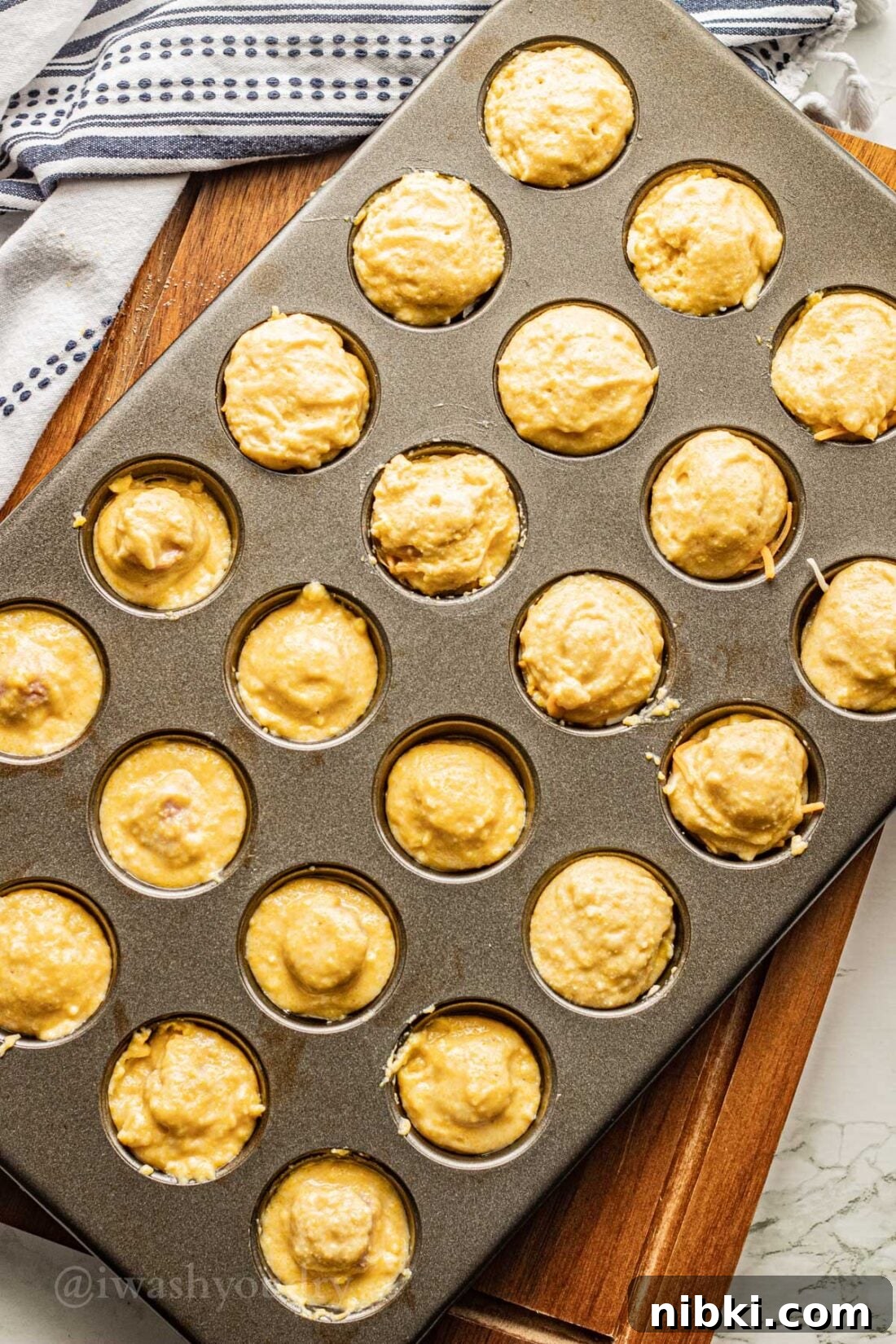 Crispy Mini Corn Dogs Recipe 7 hot dogs covered in corn dog batter ready for the oven.
