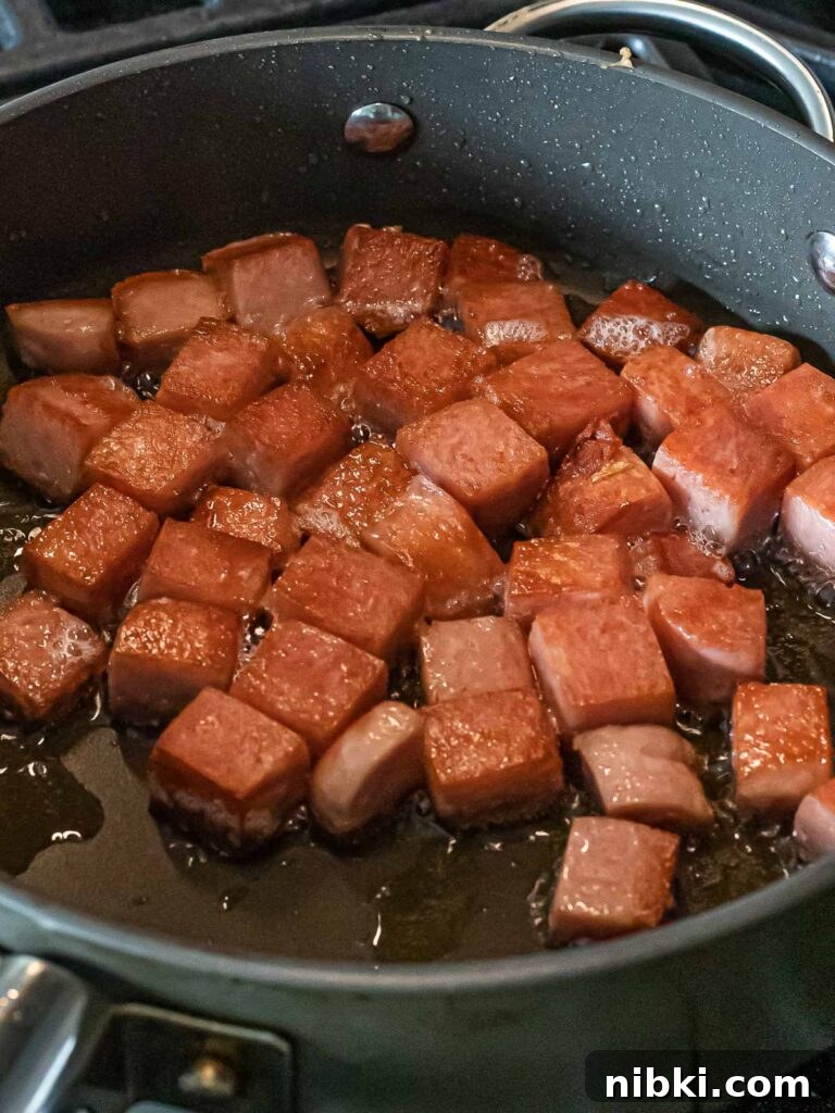 Spicy Kimchi Fried Rice with Crispy Spam 5 cubes of spam frying in a nonstick pan