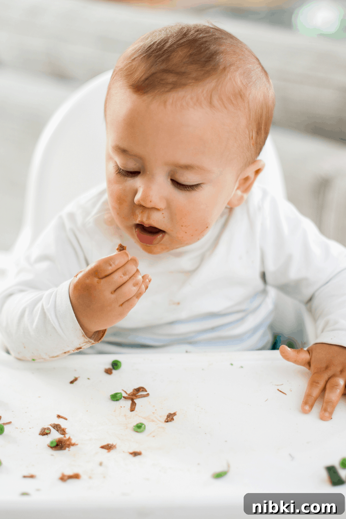 What to Feed an 8-Month-Old (and 9-10 Month Babies) 4 9 month old baby eating finger foods peas and shredded beef in highchair