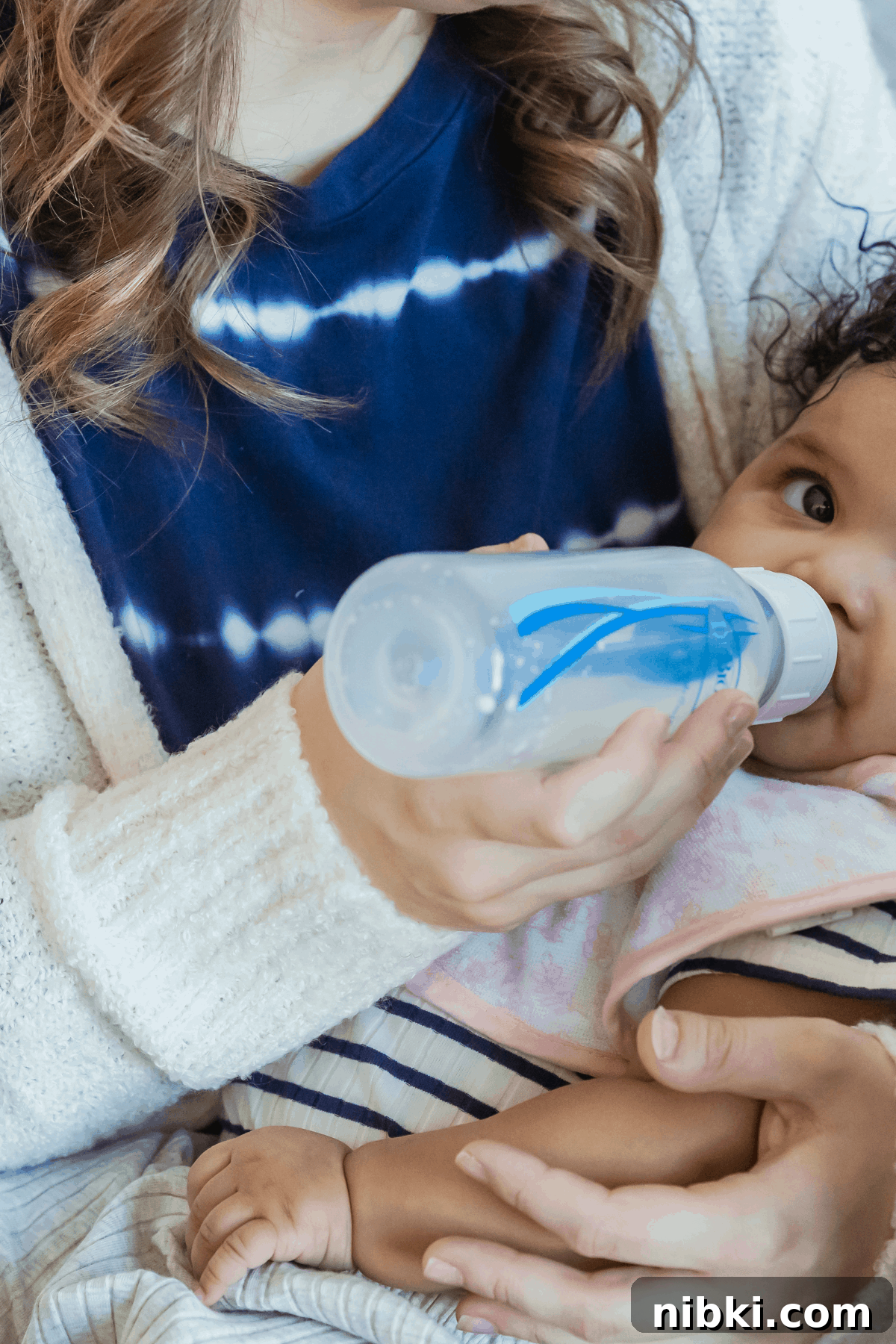 What to Feed an 8-Month-Old (and 9-10 Month Babies) 5 8 month old baby drinking dr browns bottle in mother's arms before offering solids