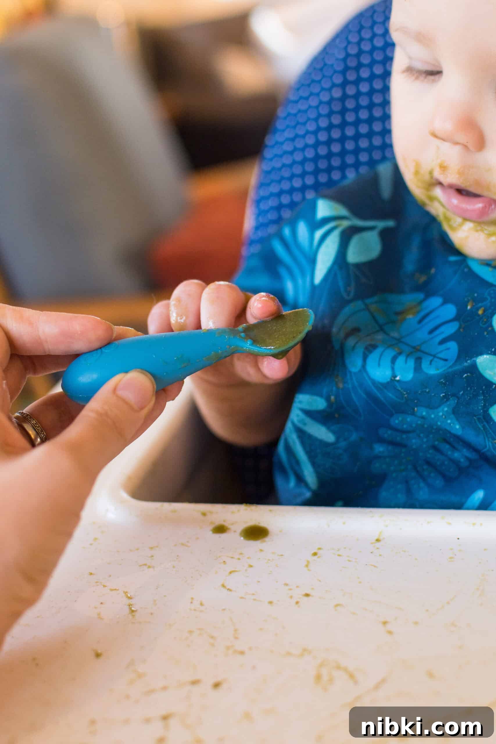 What to Feed an 8-Month-Old (and 9-10 Month Babies) 8 baby self feeding puree with blue ezpz tiny spoon in high chair with blue bib