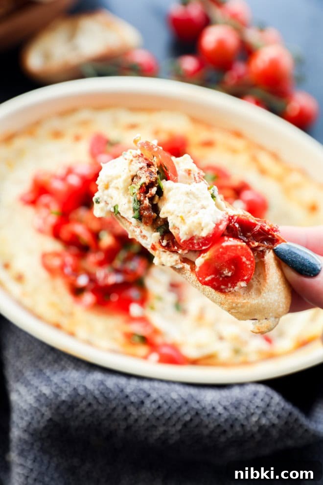 crostini with melted cheese mixture and tomatoes and fresh herbs on it