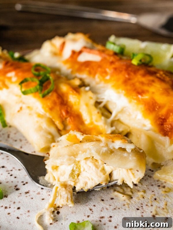 Creamy Avocado Coleslaw Recipe for Summer BBQs 11 White chicken enchilada on a plate with a fork. Limes on the side and ready to eat. A bite taken out of the enchiladas with a fork.