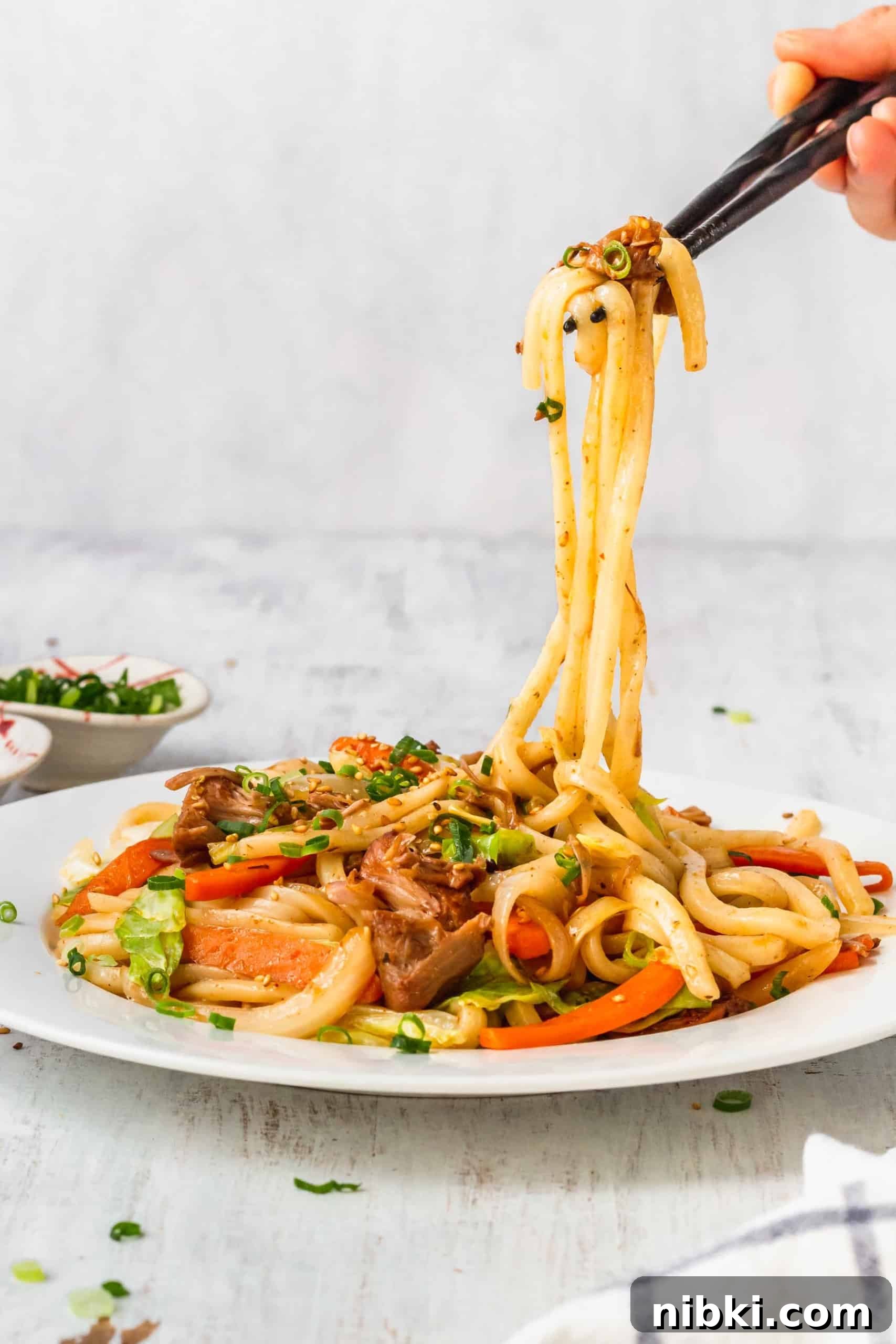 Vegan massaman noodles being lifted with chopsticks