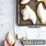 baking sheet with pop tart ghosts and one broken ghost outside the sheet with a hand reaching towards it