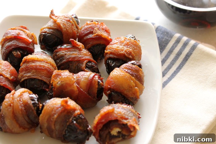 Crispy Bacon-Wrapped Dates Recipe 4 Bacon-wrapped dates on a baking sheet