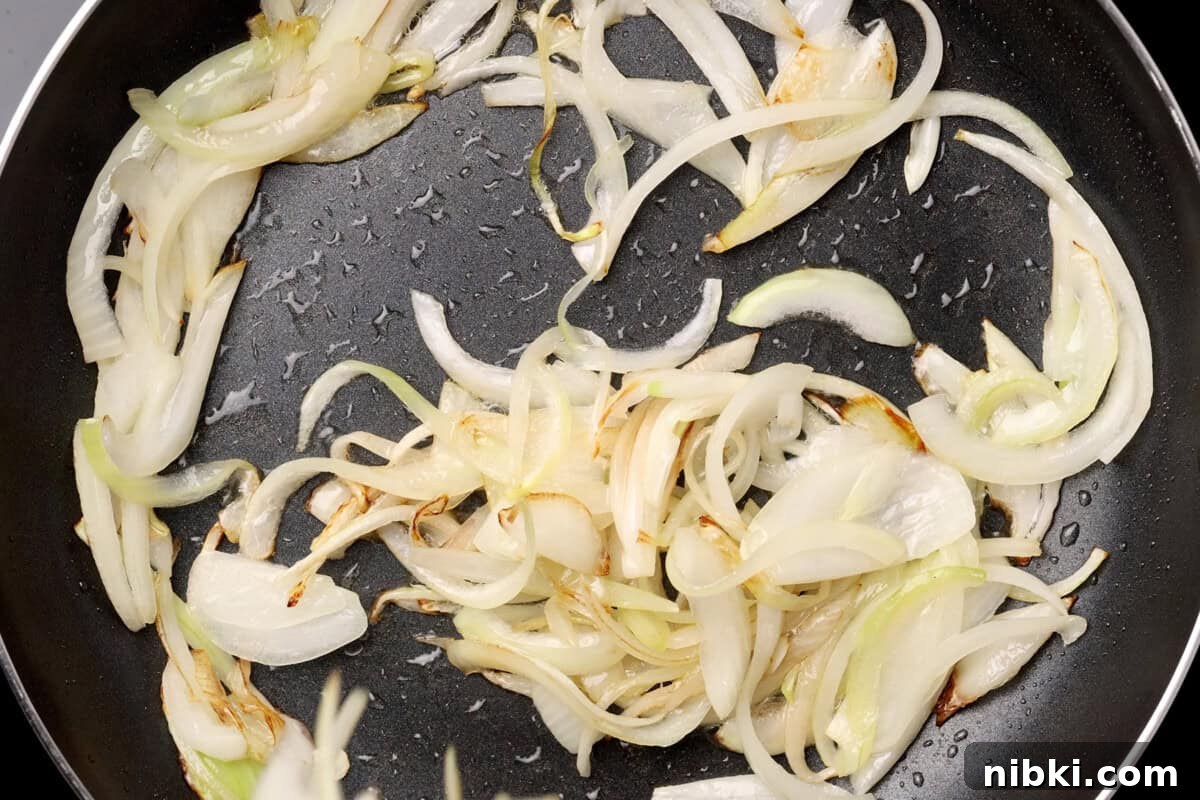 Cumin-Spiced Lamb Recipe: Tender, Flavorful Roast 9 Onions sautéing in a pan