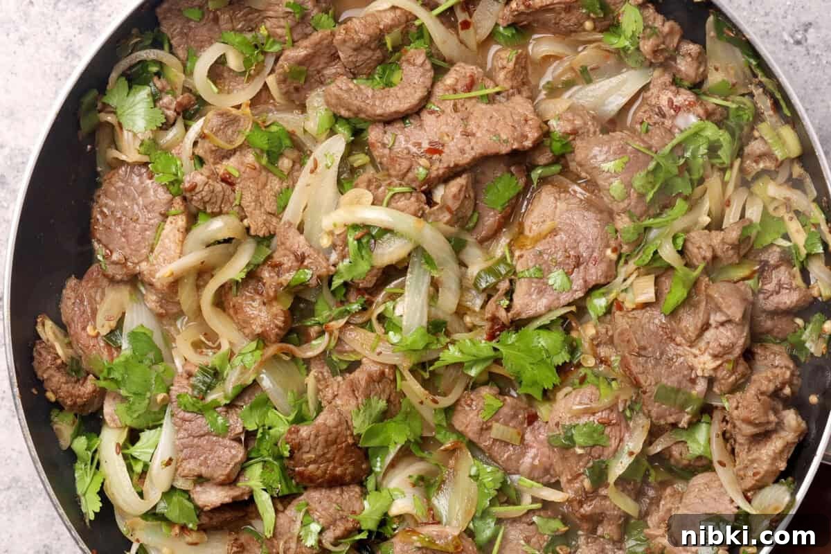 Cumin-Spiced Lamb Recipe: Tender, Flavorful Roast 10 Finished spiced meat and onions garnished with cilantro