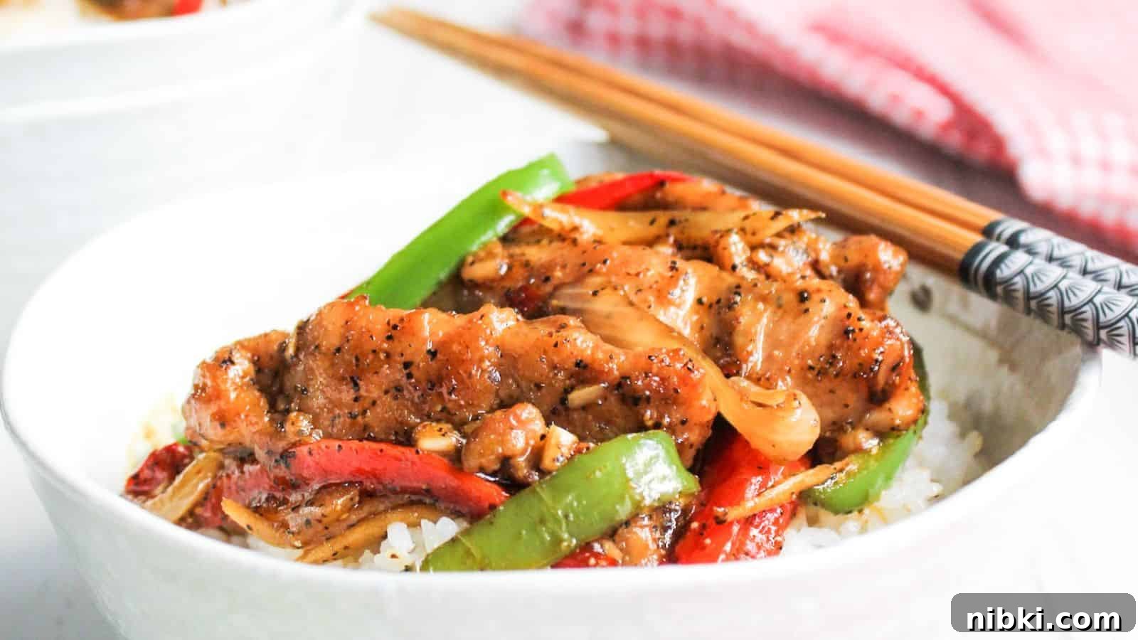 17 Affordable Chicken Recipes That Stretch Your Grocery Budget 2 A bowl of chicken stir-fry with vegetables served over rice, accompanied by chopsticks.