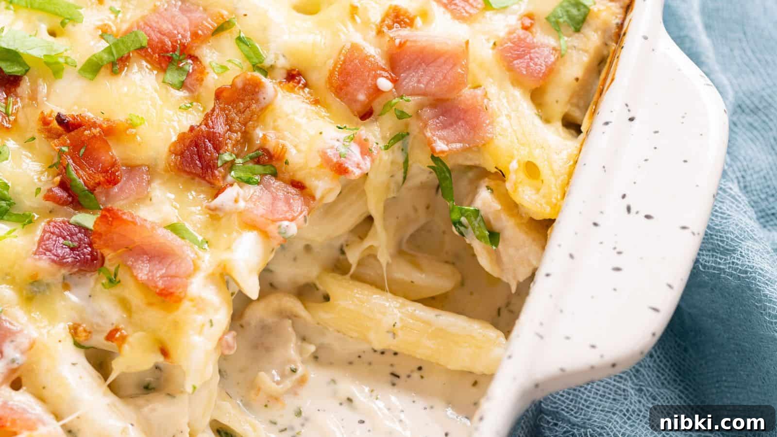 17 Affordable Chicken Recipes That Stretch Your Grocery Budget 12 Creamy baked pasta with melted cheese and bacon bits garnished with herbs in a white ceramic dish.