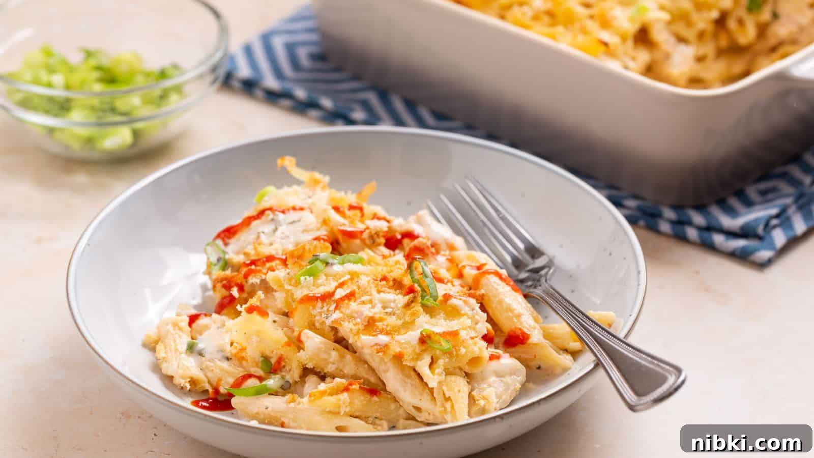 17 Affordable Chicken Recipes That Stretch Your Grocery Budget 7 A plate of cheesy baked pasta and chicken casserole served with chopped scallions, accompanied by a baking dish and fork.