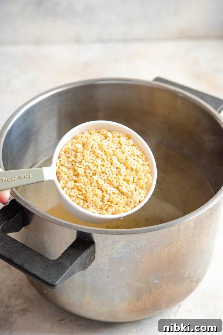 Adding pastina pasta to chicken soup A photo of adding pastina pasta to chicken soup