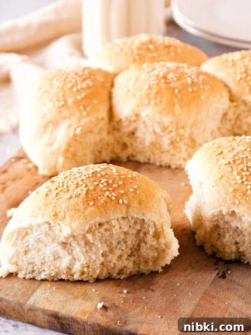 Wooden board with several dinner rolls. White and gray background.